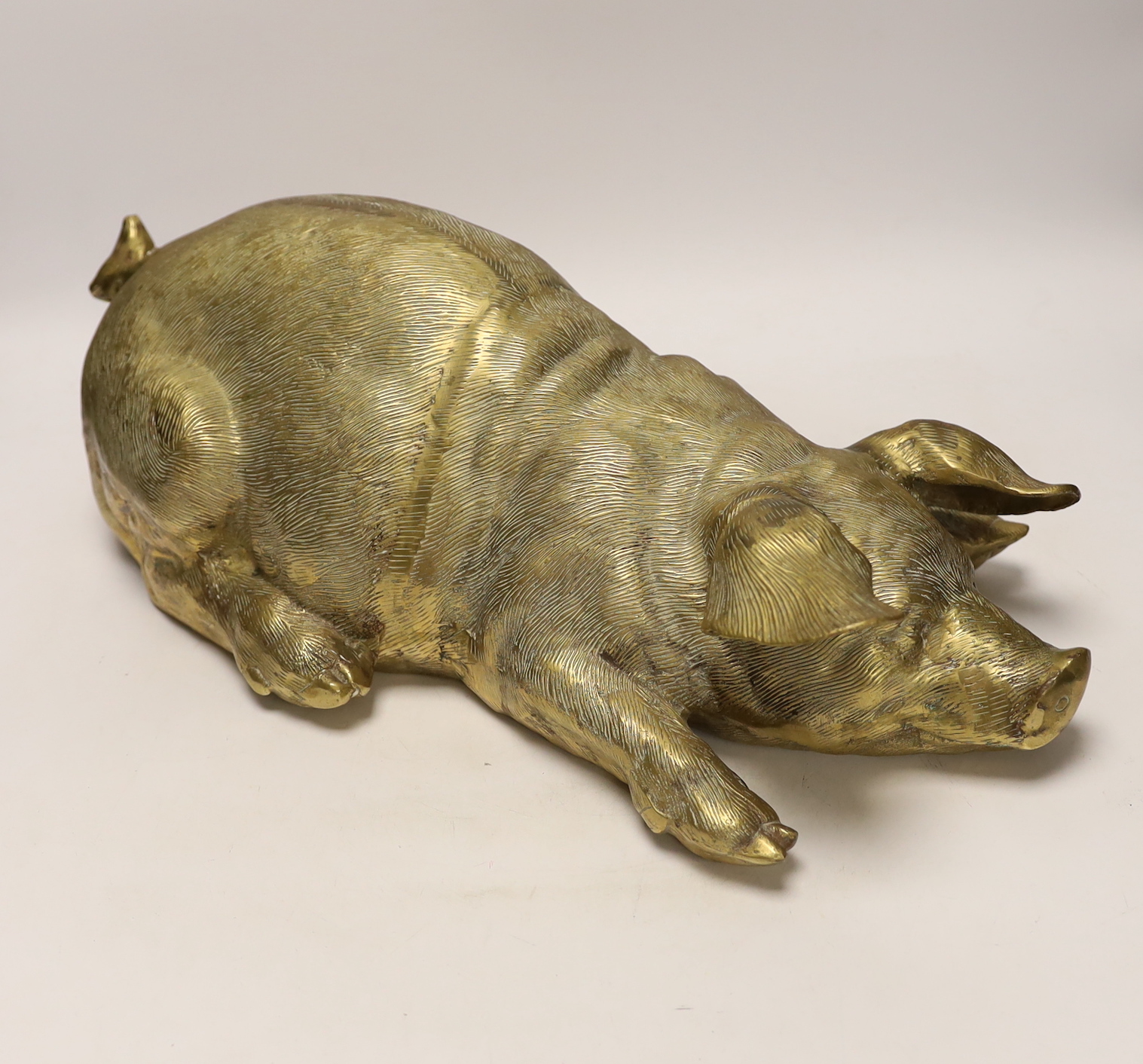 A large hollow cast brass model of a recumbent pig, 46cm long